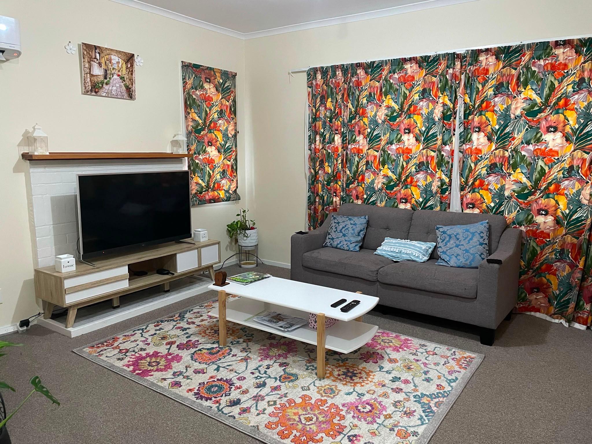 Styled floral lounge with colourful rug and grey sofa